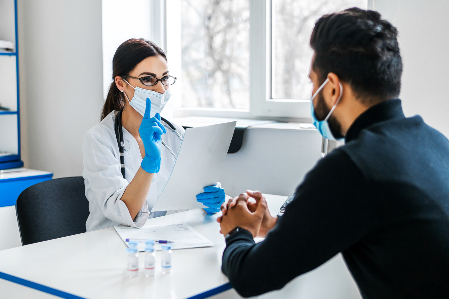 A Female Doctor Consults Her Patient And Holds Documents In Her